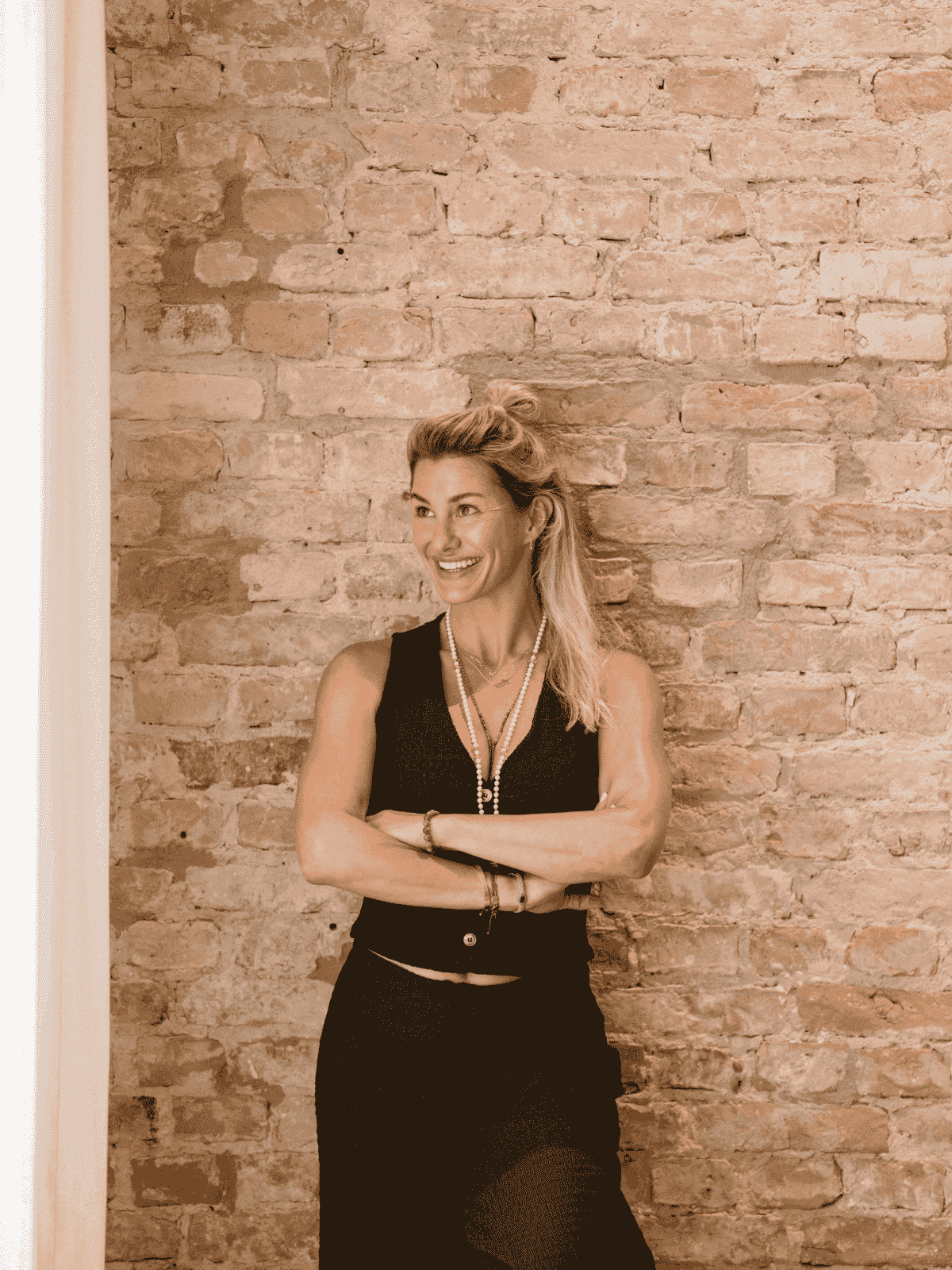 Dominique Scharax, lachend vor Backsteinwand